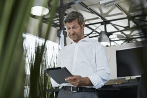 Surprised businessman in office looking at digital tablet