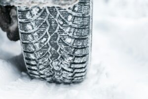 Winter tyre. Car tires on winter road covered with snow.