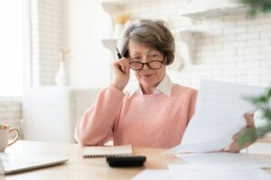 Stressed caucasian old elderly senior old grandmother woman paying bills online, having debt