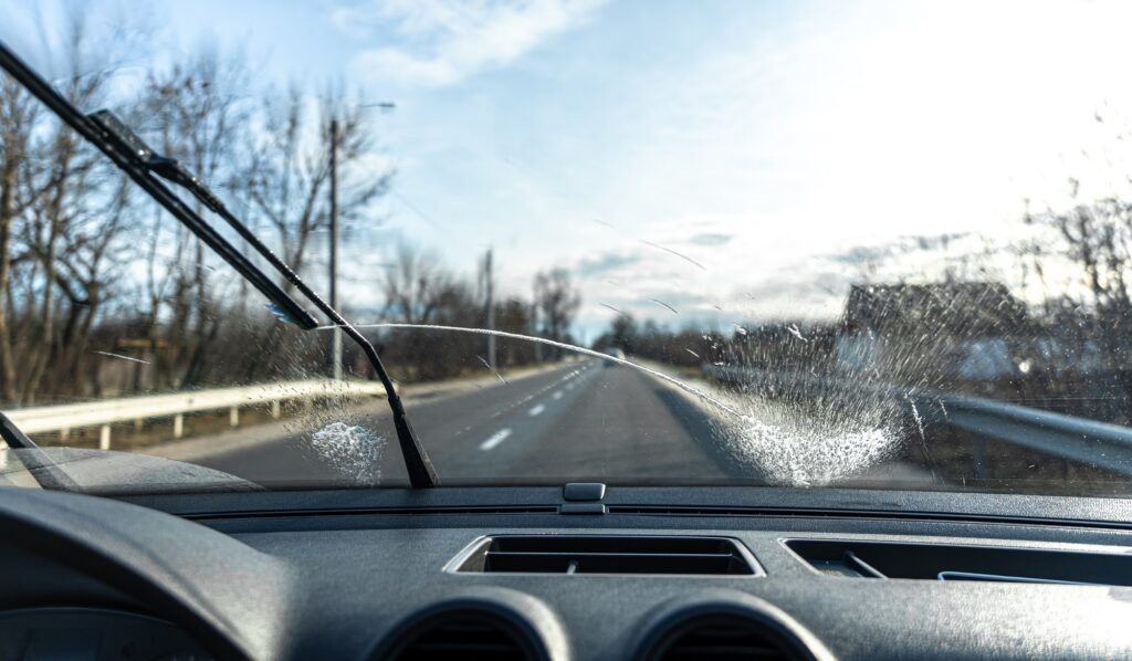 Car wipers clean windshields when driving in sunny weather.