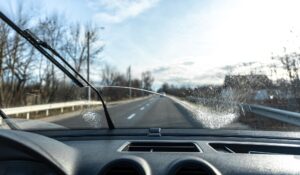 Car wipers clean windshields when driving in sunny weather.